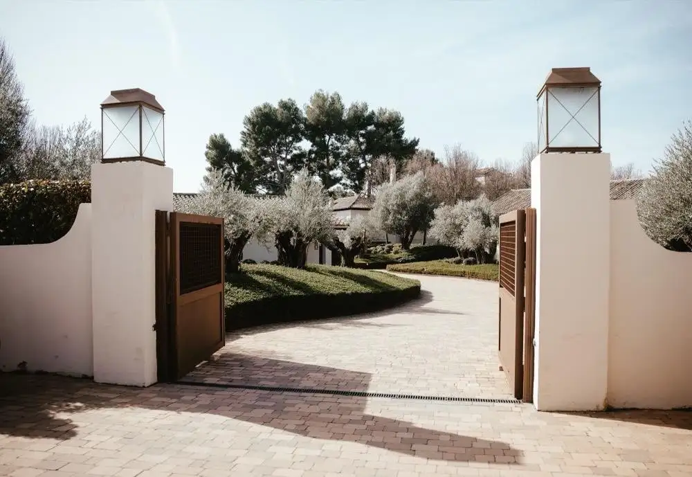 El portalón de la finca, con dos farolas sobre los pilares y el camino que se pierde entre olivos